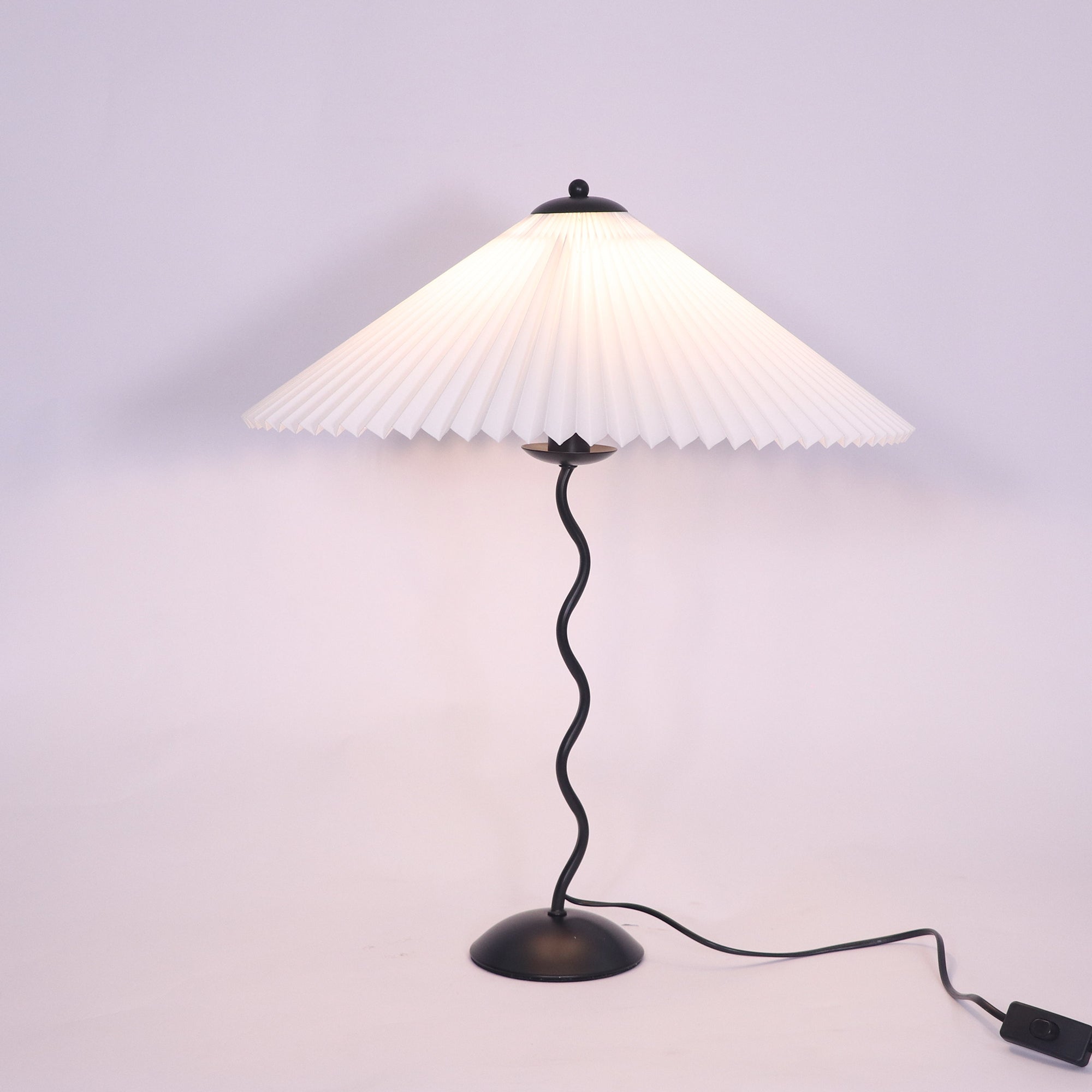 Squiggle table lamp lit on a side table with warm glow