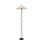 Squiggle floor lamp with wavy black base and fabric shade in a room corner