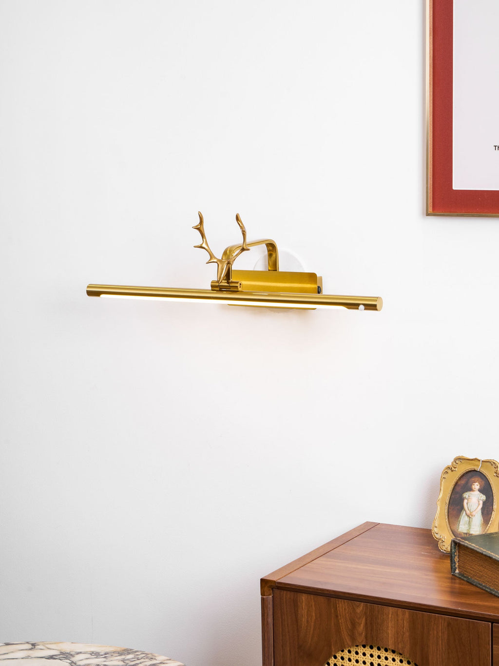 Picture light sconce highlighting a framed print on a feature wall
