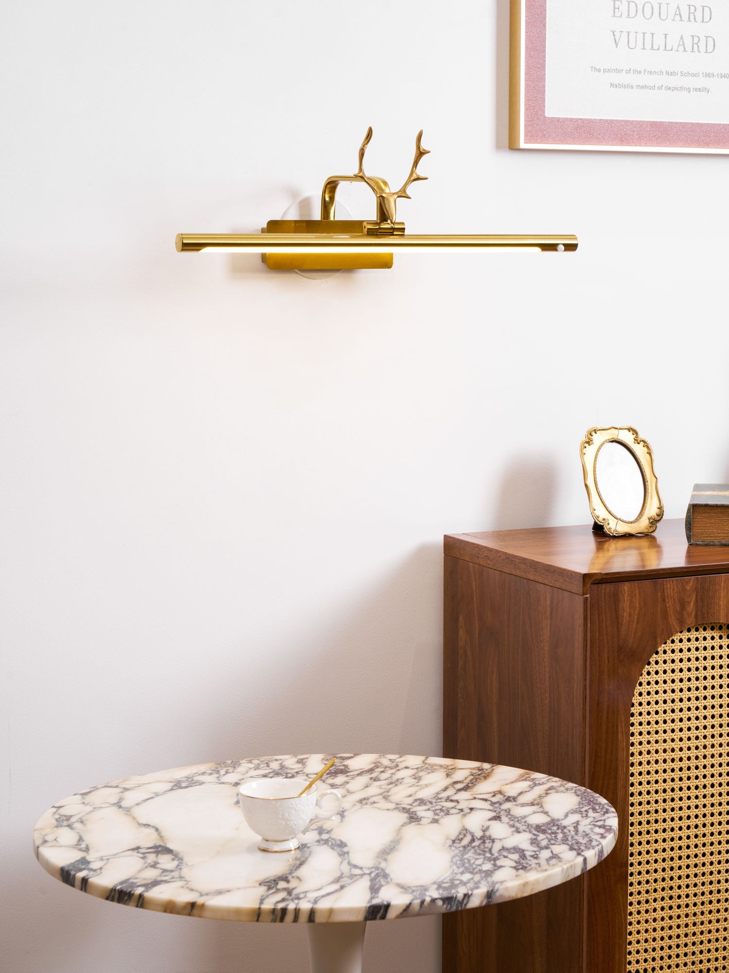 Stag horn wall sconce shown lit above a horizontal art frame