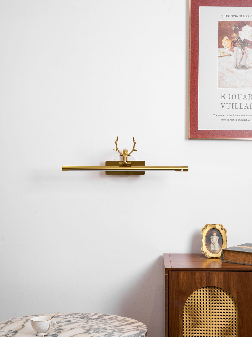 Stag horn picture light illuminating artwork in a cosy room setting