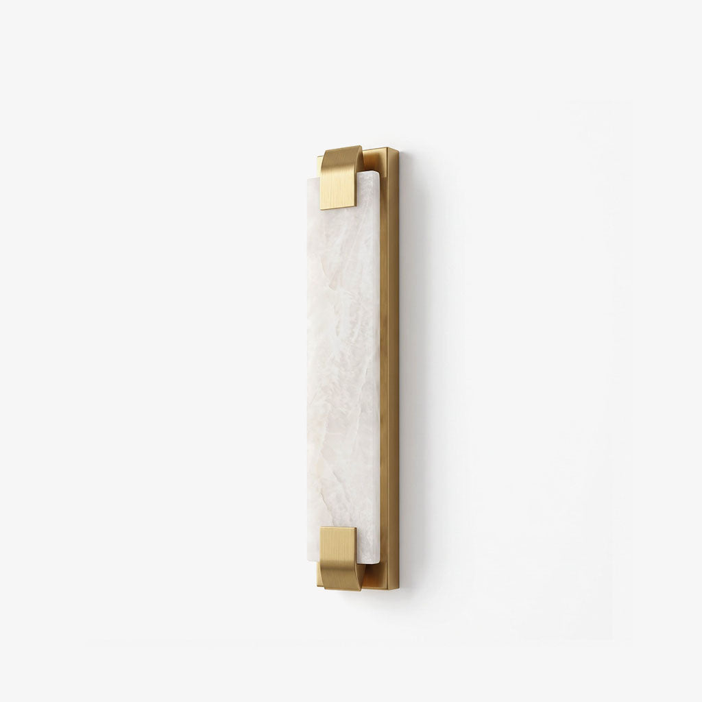 An angled studio view of this Clérachic panel sconce in brass finish, showing the metal clips that grip its panel.