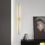 Linear metal sconce casting a tall column of warm light