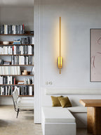 Linear metal wall sconce mounted in a modern entryway