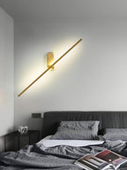 Brass stick wall sconce lit beside a stairway