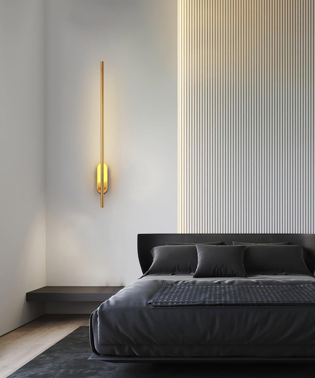Slim metal wall sconce lit beside a framed picture