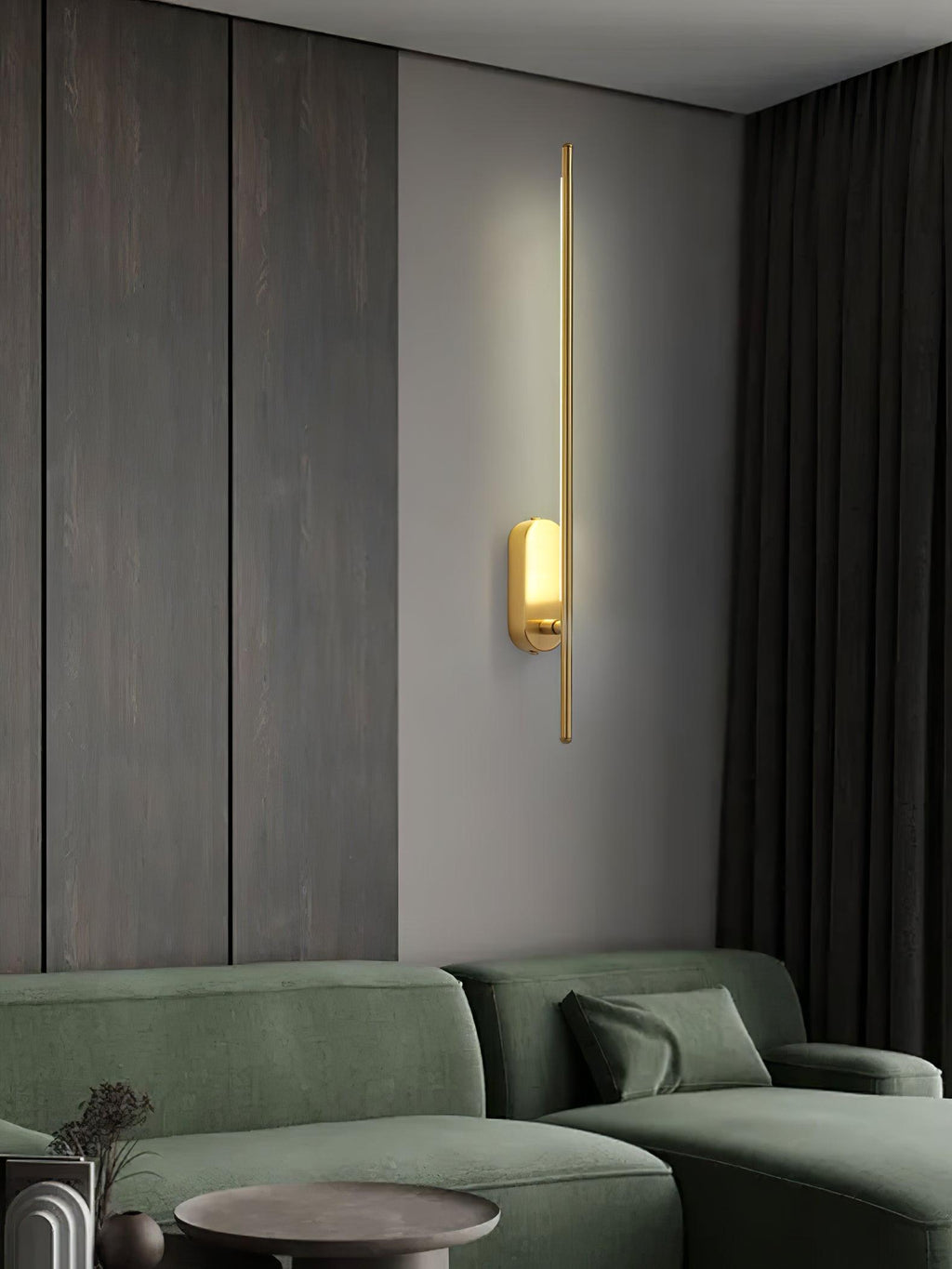 Stick-shaped wall sconce in brass shown in a styled room