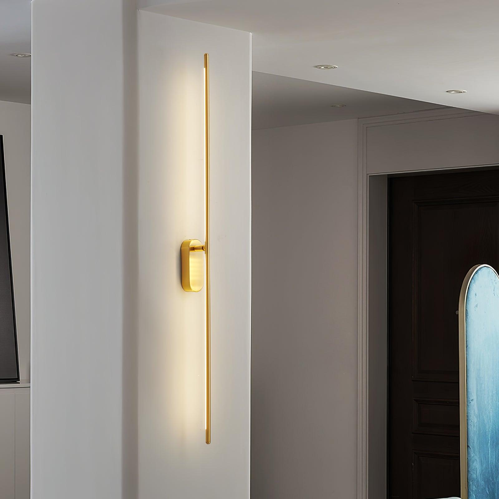 Brass stick wall sconce shown lit in a minimalist interior