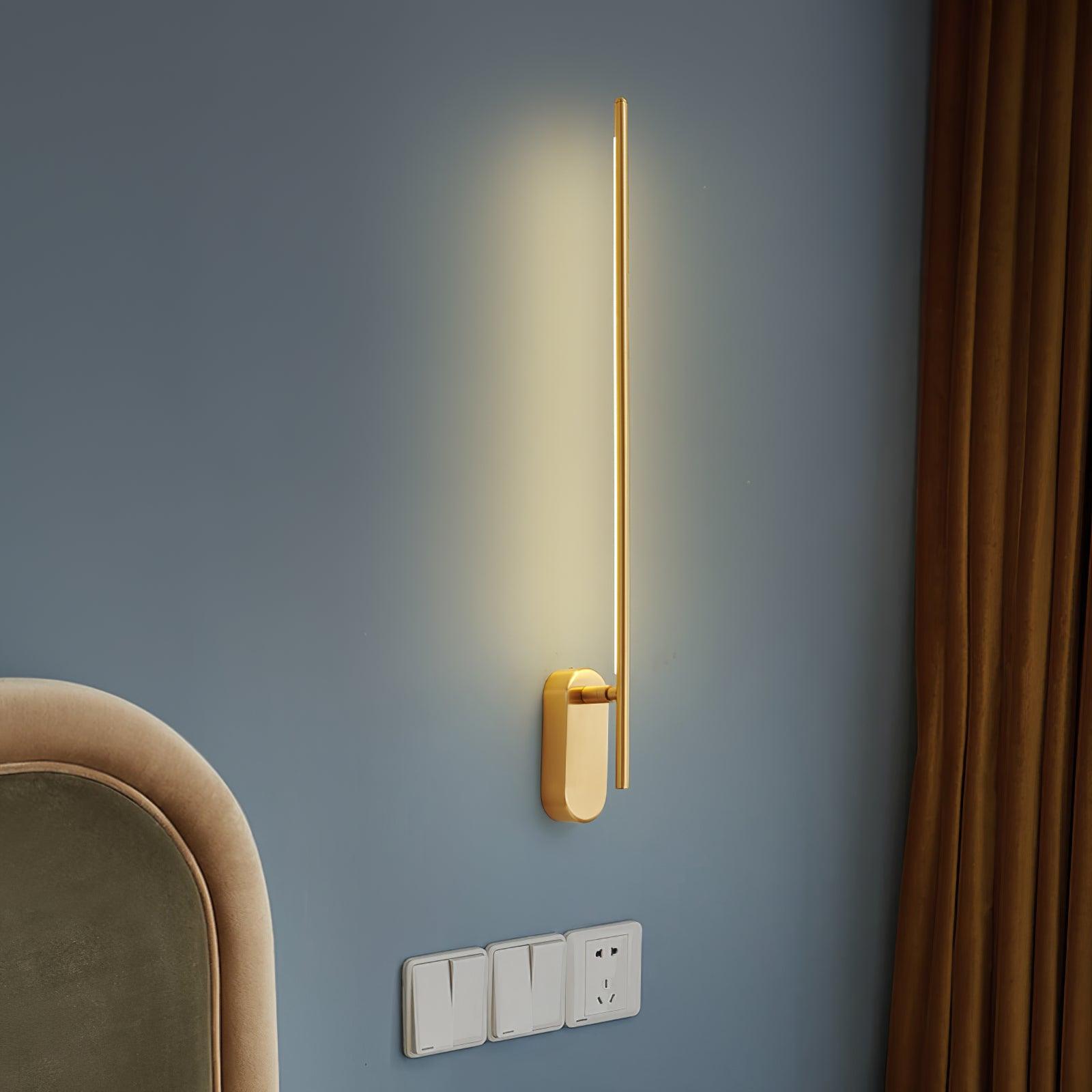 Linear metal sconce in black finish glowing in a hallway