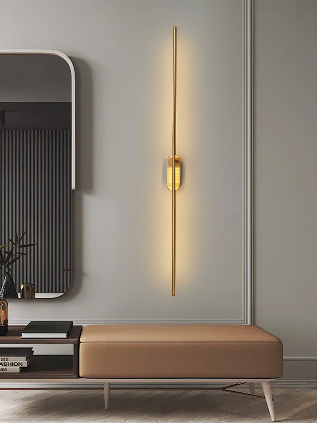 Slim linear sconce in brass against a pale plaster wall