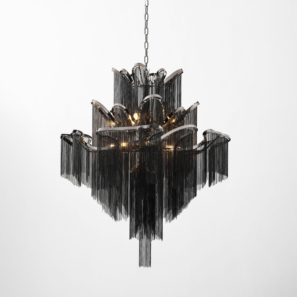 A black-chain Clérachic chandelier, lit, its scalloped tiers stepping outward against a plain white backdrop.