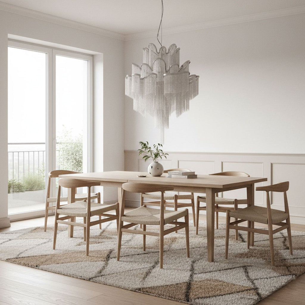 Above a wooden dining table and chairs, this silver Clérachic chandelier hangs lit with a balcony view beyond.