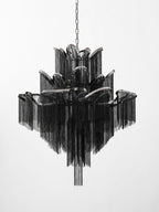 Seen from a slightly wider angle, this lit black Clérachic chandelier shows its full stepped tiers on white.