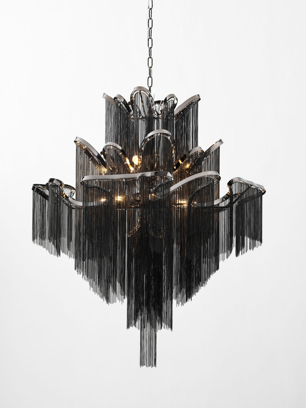 In black chain, this lit Clérachic chandelier steps outward in tiers against a plain white backdrop.