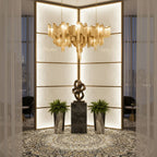 Lit gold chain tiers on this Clérachic chandelier fill a modern corner nook with ferns and a dark sculpture.