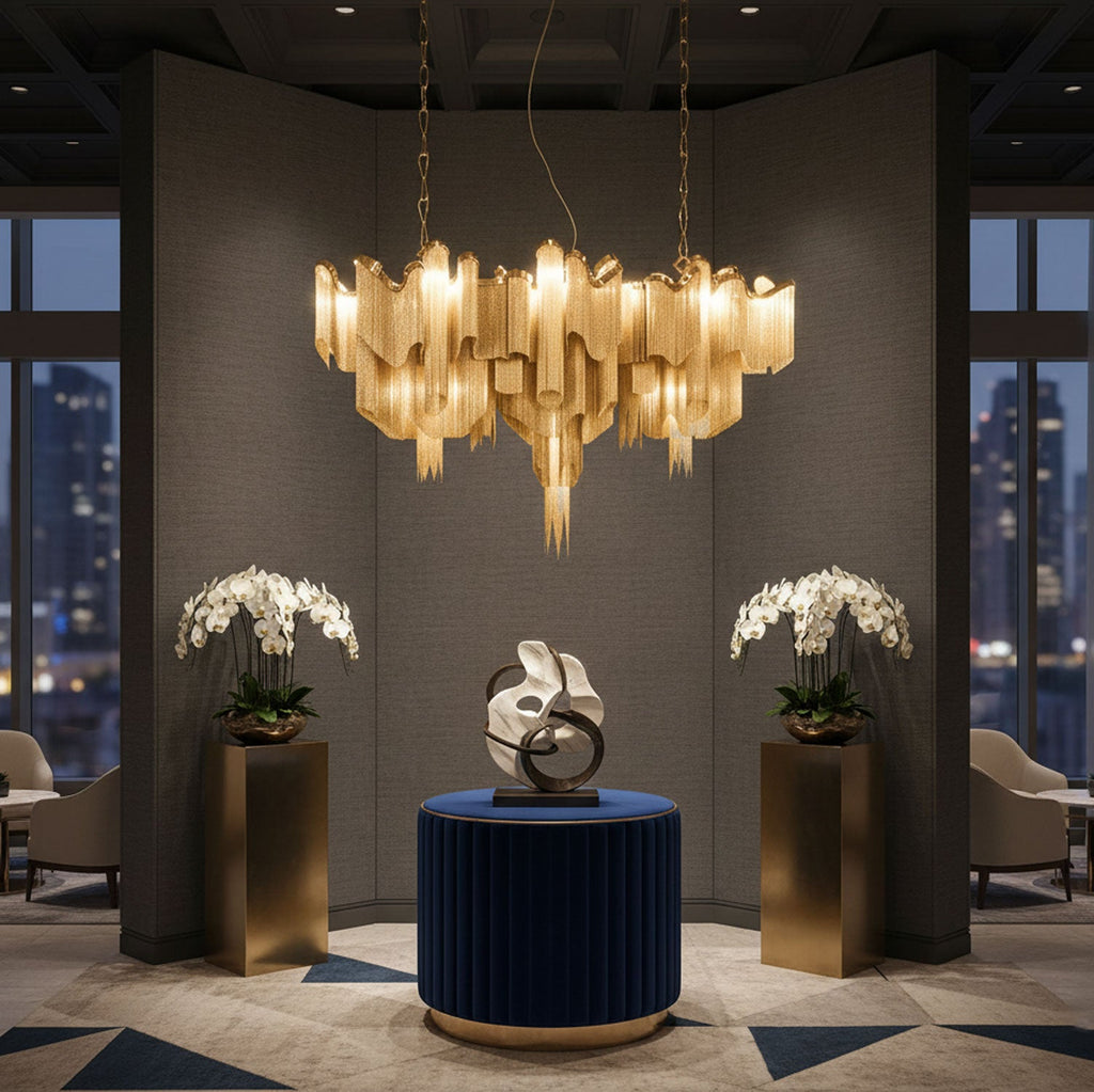 At night, this gold Clérachic chandelier lights a dim lounge flanked by potted orchids and a sculptural centrepiece.