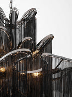Close view of the curled black chain tiers and nickel arches on this lit Clérachic chandelier.