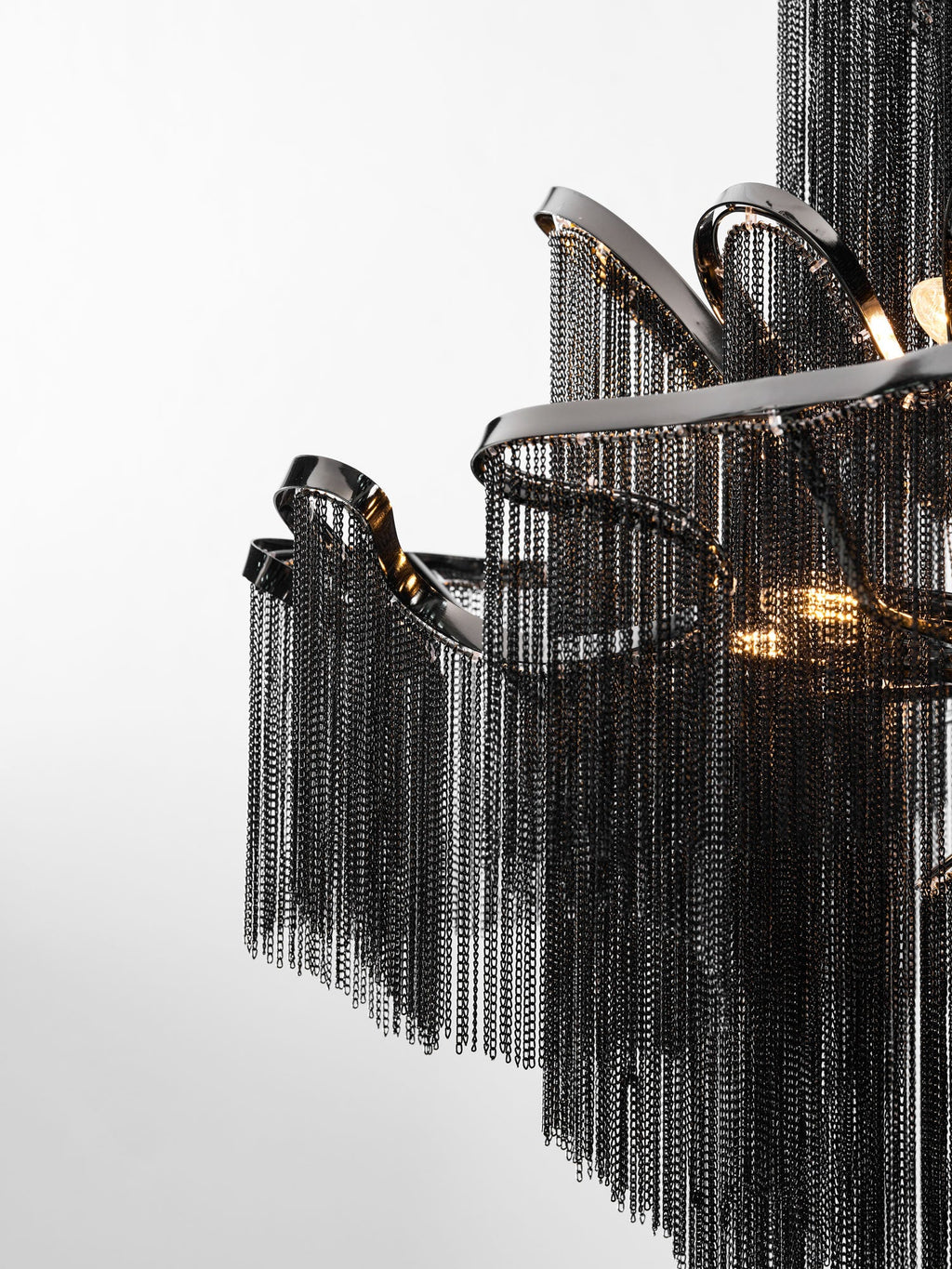 A tight close-up shows the black chain fringe spilling from curved nickel rods on this lit Clérachic chandelier.