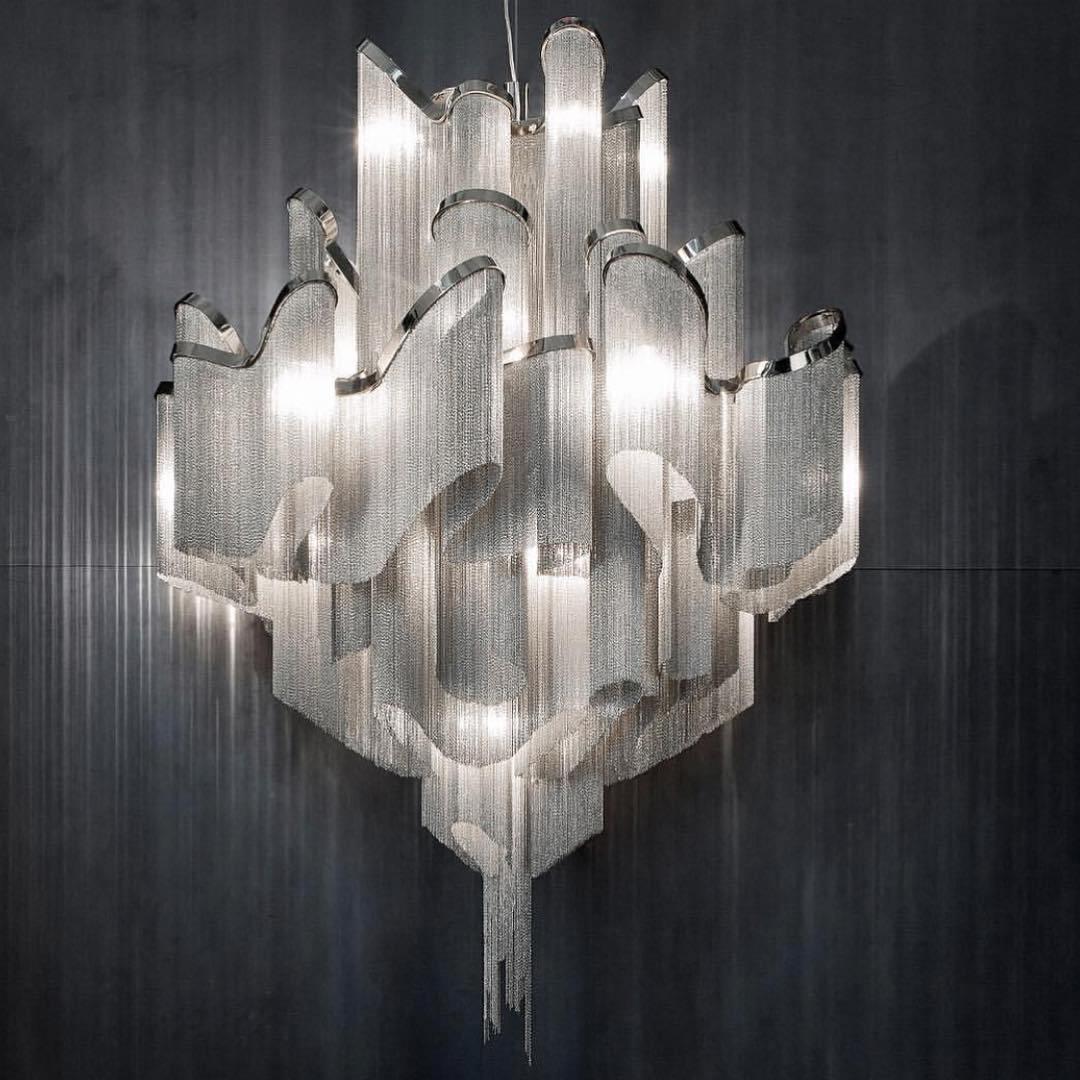 Close against a dark grey wall, this lit silver Clérachic chandelier shows its full tiered chain structure.