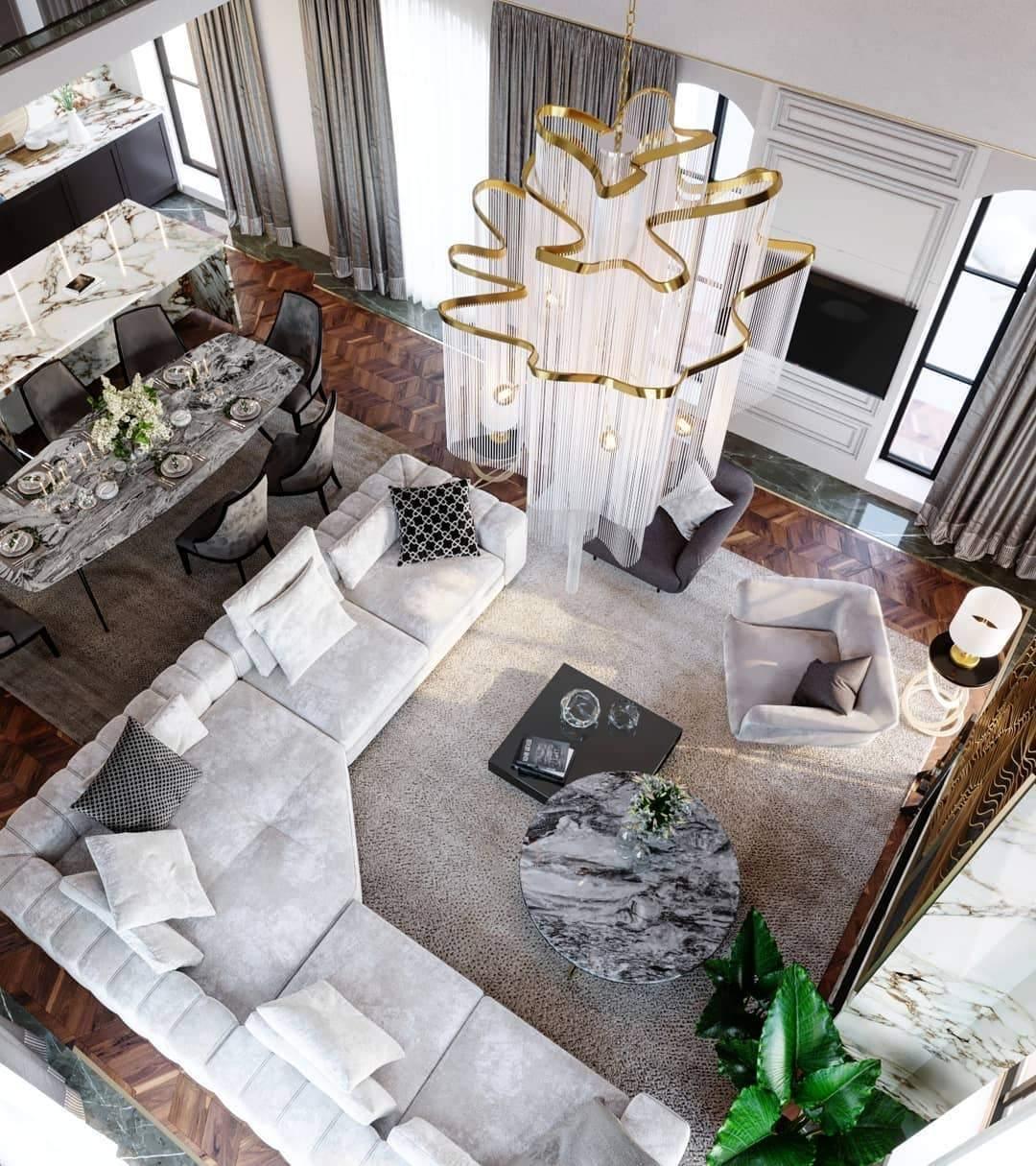 Viewed from above, this lit gold Clérachic chandelier's chain tiers form a wave-like shape over an open-plan lounge.