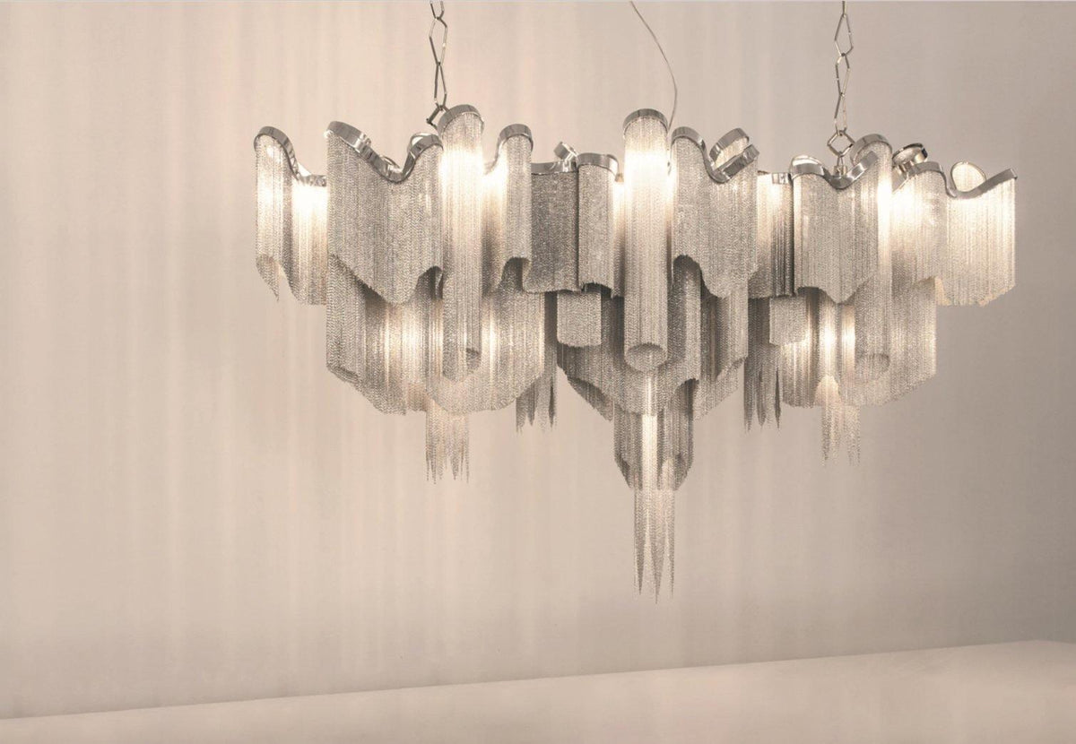 Against a warm plain backdrop, this lit silver Clérachic chandelier is shown with its tiers stepping outward.