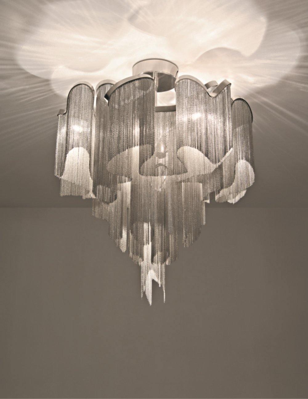 Backlit dramatically, this silver Clérachic chandelier's tiers glow bright against a hazy pale backdrop.