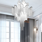 Sheer curtains and a panelled wooden door frame this lit silver Clérachic chandelier nearby.