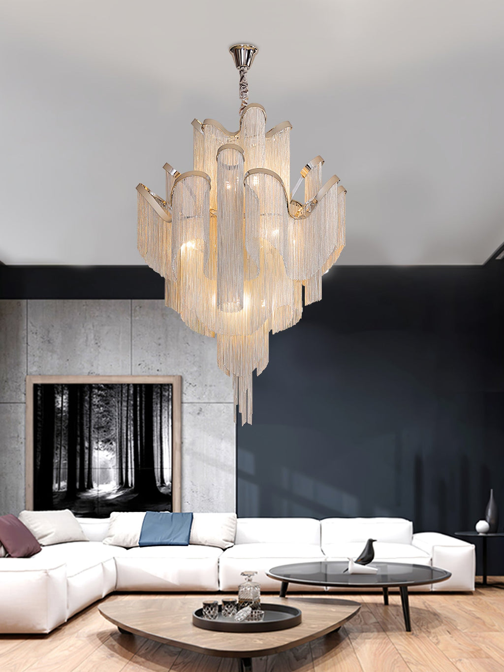 A white sofa and black side table sit beneath this lit gold Clérachic chandelier in a bright living room.