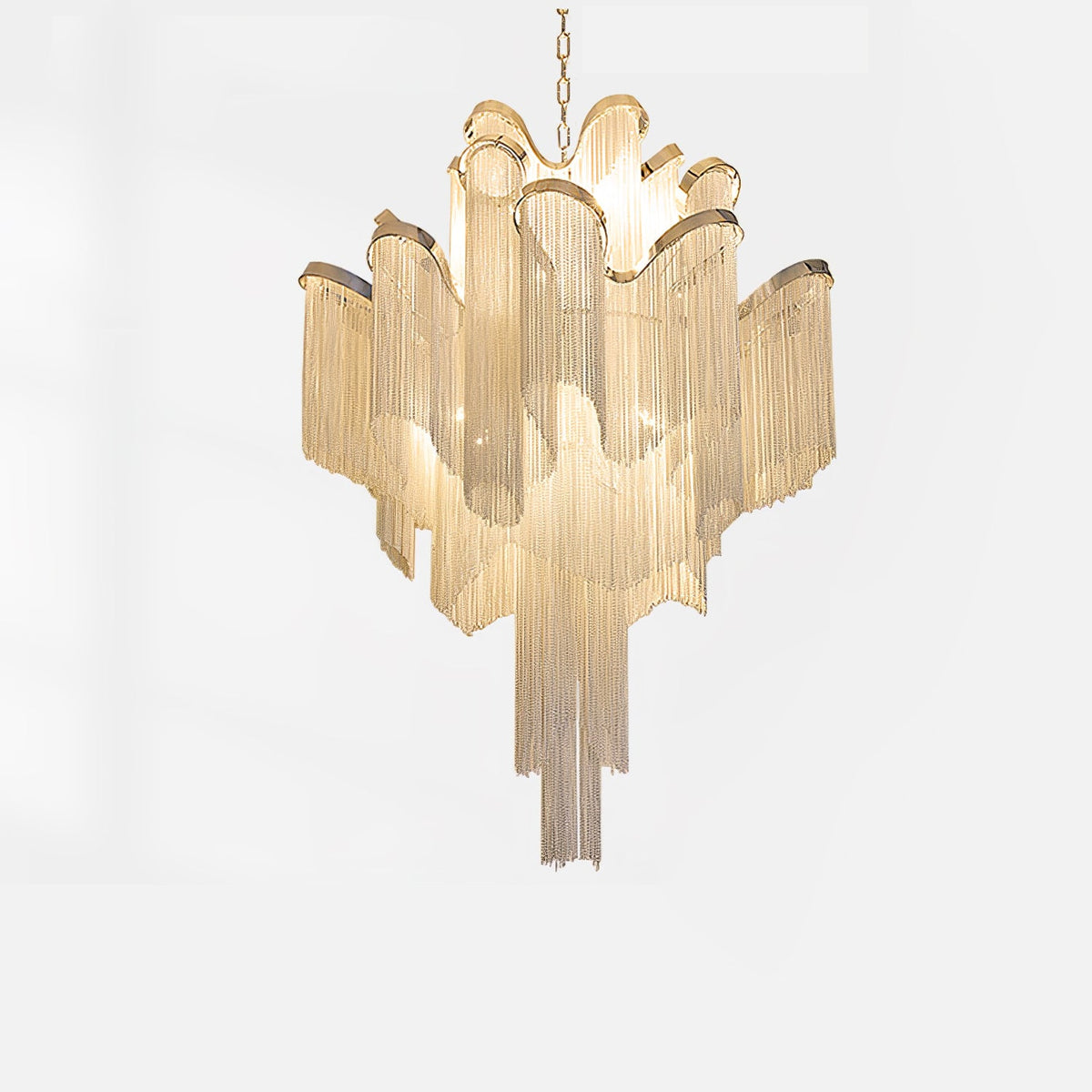This gold Clérachic chandelier, lit, is shown against a white backdrop with its full tiered chain fringe.