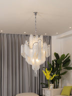 Cropped close, this lit silver Clérachic chandelier shows the full drop of its chain against grey curtains.