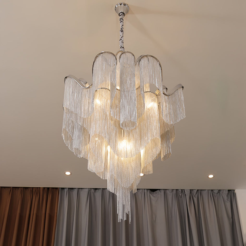 Against beige curtains, this lit silver Clérachic chandelier glows beneath recessed ceiling lights.