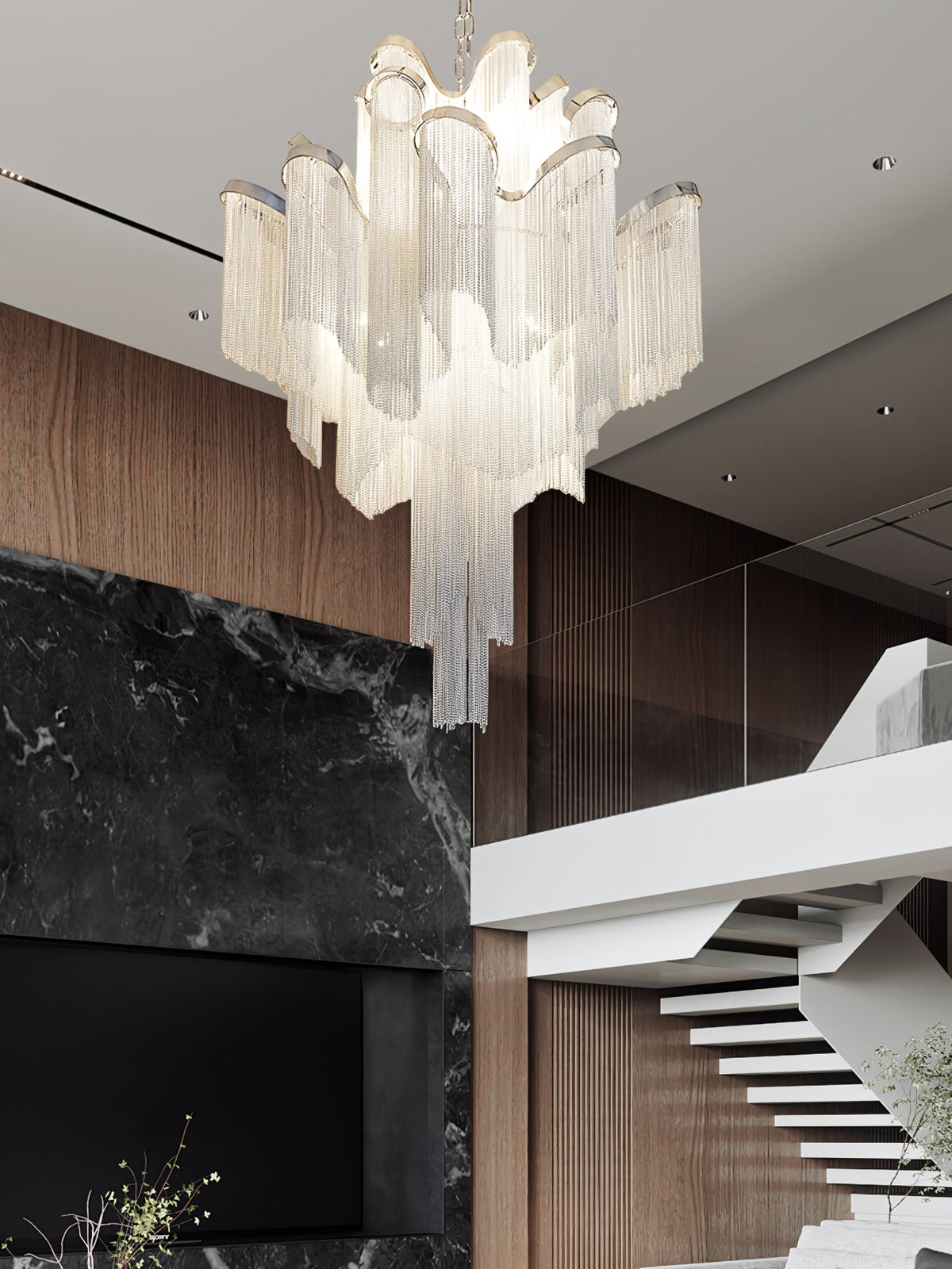 Near a dark marble fireplace and pale wooden staircase, this lit silver Clérachic chandelier hangs overhead.
