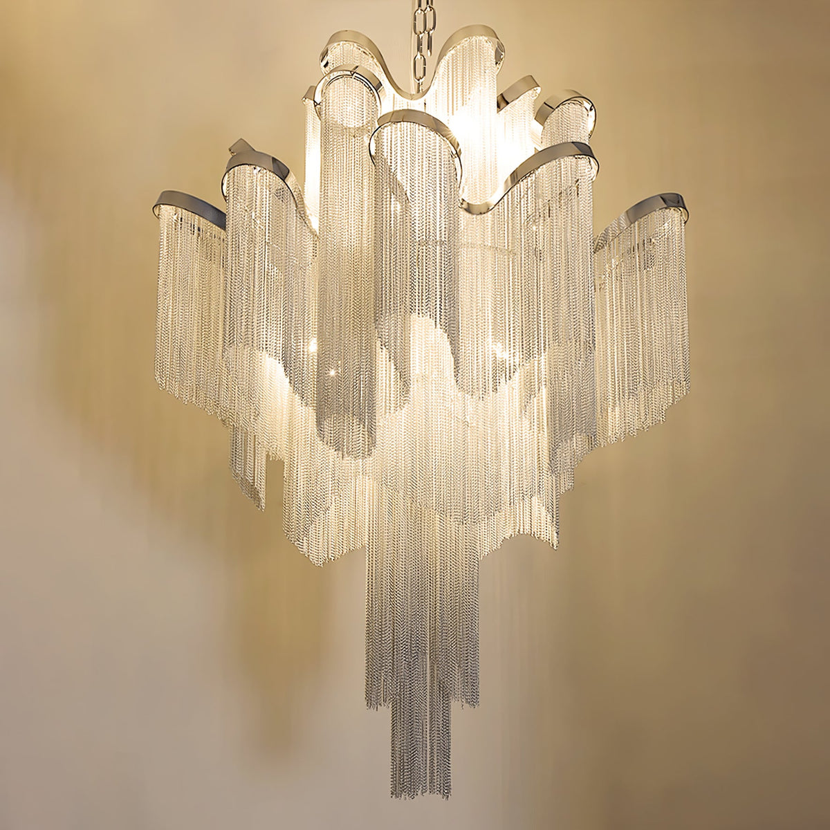 Close against a warm wall, this lit gold Clérachic chandelier shows its full tiered chain fringe.