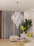 A sage-green cushion and framed photo sit beneath this lit silver Clérachic chandelier in a living room.