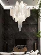 Set against a black stone wall near a dark fireplace, this lit silver Clérachic chandelier glows softly.