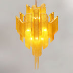 Trailing downward on a white backdrop, this lit gold Clérachic chandelier is fully tiered.