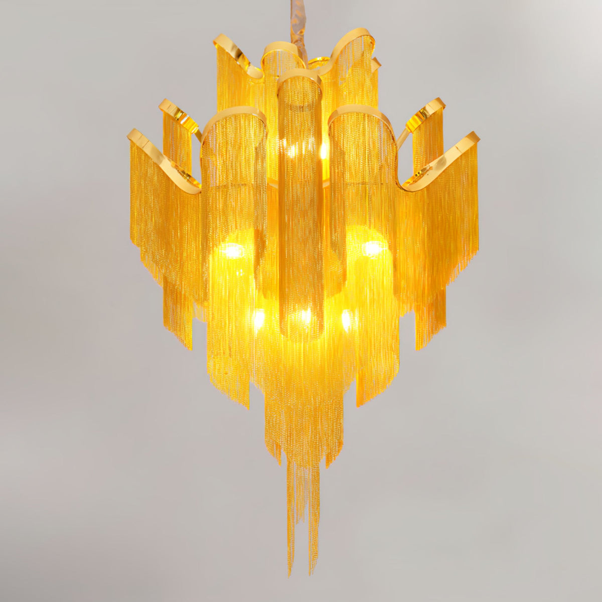 Trailing downward on a white backdrop, this lit gold Clérachic chandelier is fully tiered.