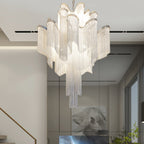 Framed horse artwork and glass display panels line the hallway beneath this lit silver Clérachic chandelier.