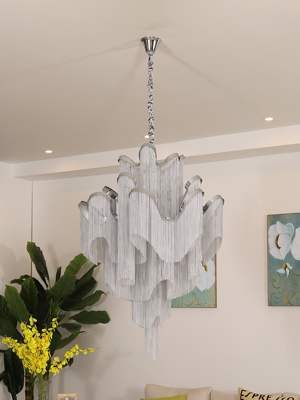 Mimosa flowers and framed botanical art sit beside this lit silver Clérachic chandelier in a cream room.