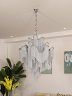 Mimosa flowers and framed botanical art sit beside this lit silver Clérachic chandelier in a cream room.