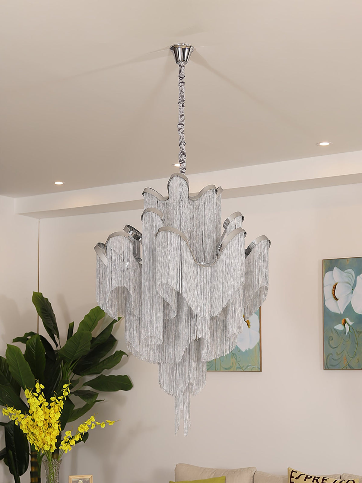Mimosa flowers and framed botanical art sit beside this lit silver Clérachic chandelier in a cream room.