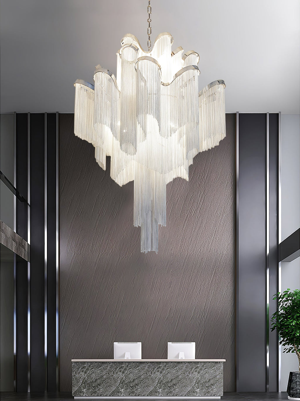 Potted plants and wood panelling surround this lit silver Clérachic chandelier in a reception area.