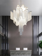 Potted plants and wood panelling surround this lit silver Clérachic chandelier in a reception area.