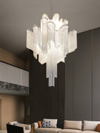 A beige sofa and patterned cushions sit beneath this lit silver Clérachic chandelier in a dark-wood living room.