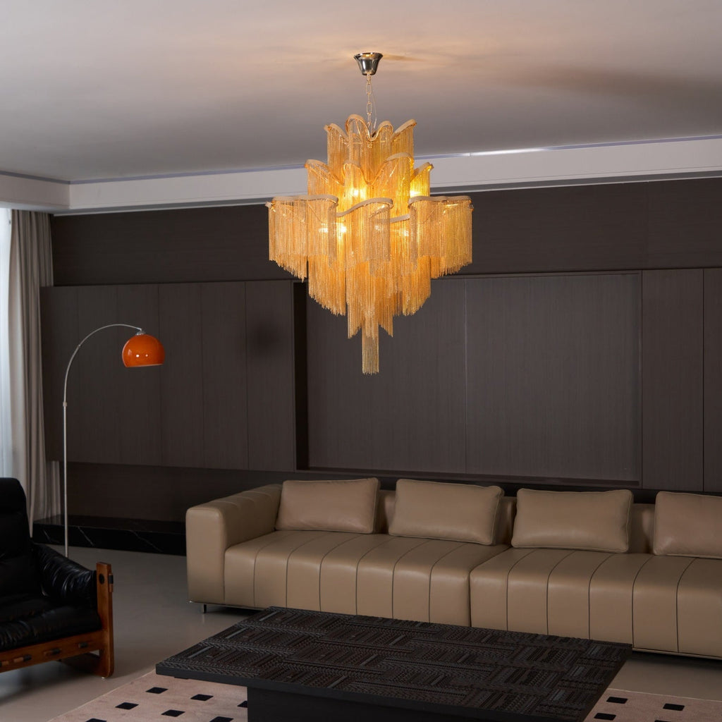 In a dark-panelled lounge with a black leather chair nearby, this lit gold Clérachic chandelier hangs overhead.