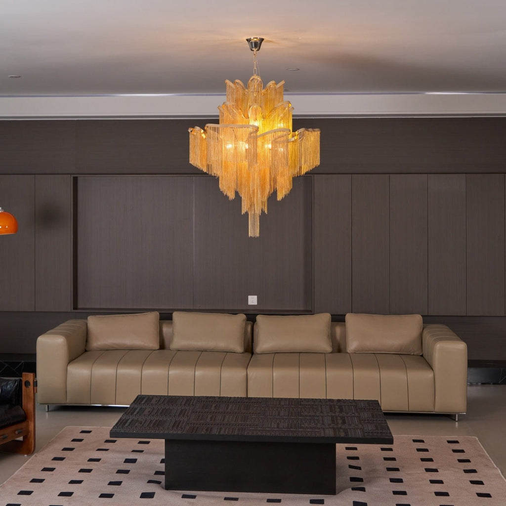 Closer to the tan leather sofa, this lit gold Clérachic chandelier hangs above a black coffee table.