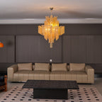 Closer to the tan leather sofa, this lit gold Clérachic chandelier hangs above a black coffee table.