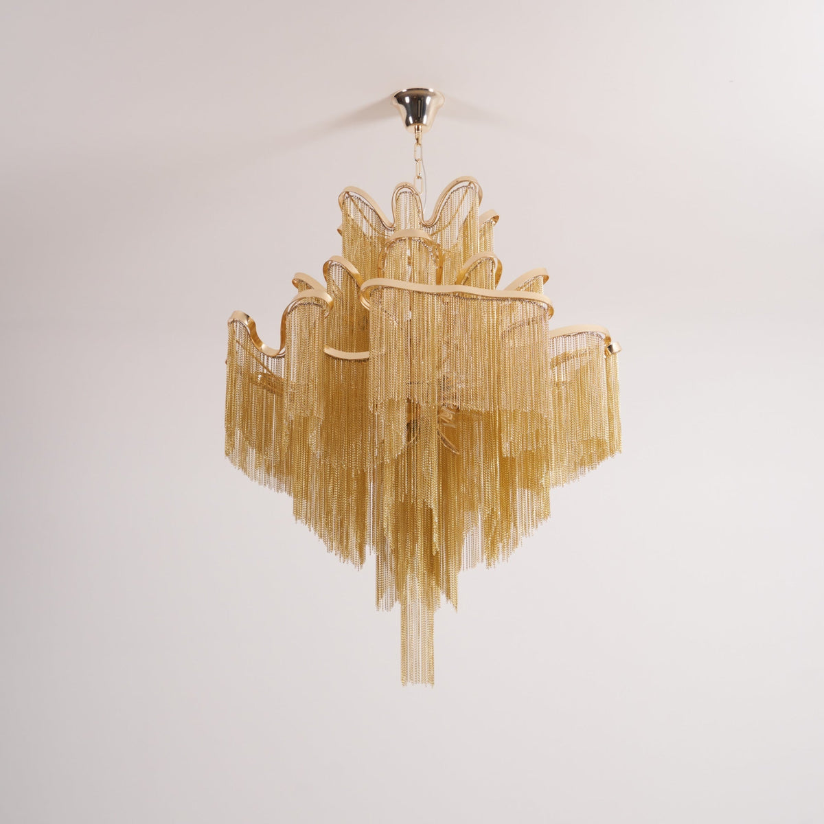 This gold Clérachic chandelier's tiers spread fully, shown unlit against a white backdrop.