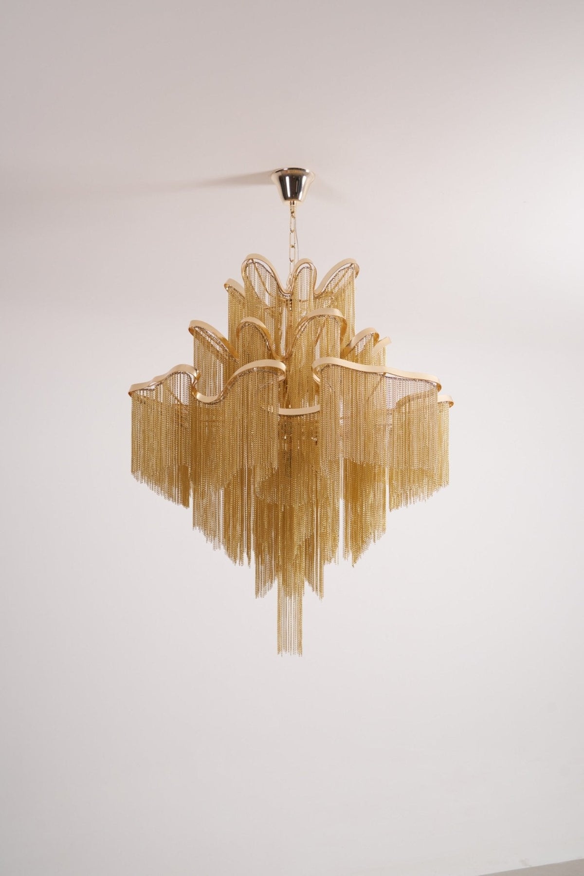 Seen from a different angle, this unlit gold Clérachic chandelier is shown against a white backdrop.