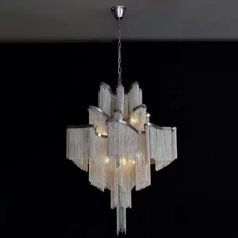 Against a plain black backdrop, this lit silver Clérachic chandelier's chain tiers glow from a slender chrome chain.